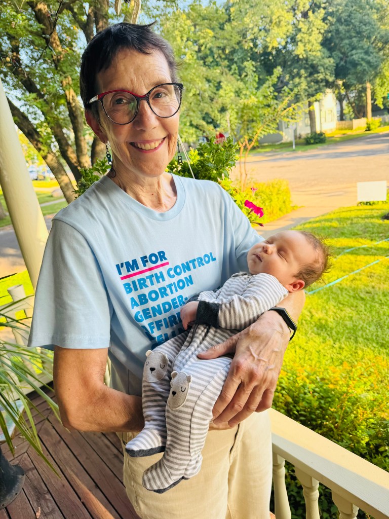 A woman in a Planned Parenthood T-shirt holds her infant grandson.