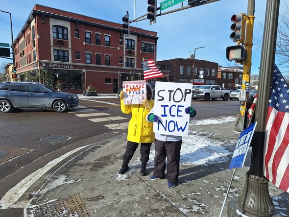 Protesters hold up homemade signs at a regular weekly protest in St. Paul.